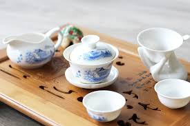 Service à thé chinois traditionnel avec gaiwan posé sur un plateau en bois, évoquant un rituel de pause-thé et de pleine conscience.